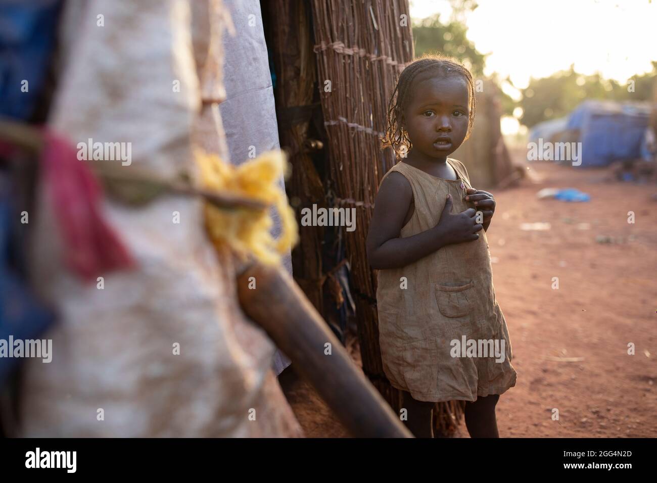 Il Senou Camp si trova al confine meridionale di Bamako, la capitale del Mali. Si tratta di uno degli otto campi informali della città e, di per sé, ospita 223 famiglie e poco più di 1.000 sfollati interni. Le famiglie che vivono qui sono fuggite dalla violenza e dall'insurrezione nella parte settentrionale del paese. Poiché la maggior parte di loro non ha mezzi di reddito o una normale fonte di cibo, la fame è una sfida quotidiana e la malnutrizione tra la sua popolazione continua ad essere diffusa. Qui, Djeneba Barry (3) si trova al di fuori del rifugio di fortuna della sua famiglia. Foto Stock