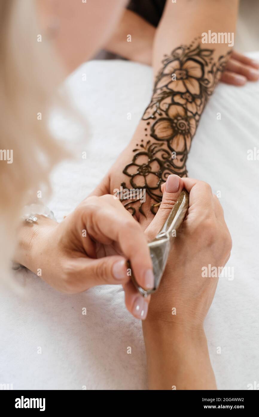 Top view art henné tatuaggio su mani femminili. Master artista che disegna mehndi arabo per sposa prima del matrimonio. Primo piano, vista dall'alto. Design floreale. Cono Foto Stock
