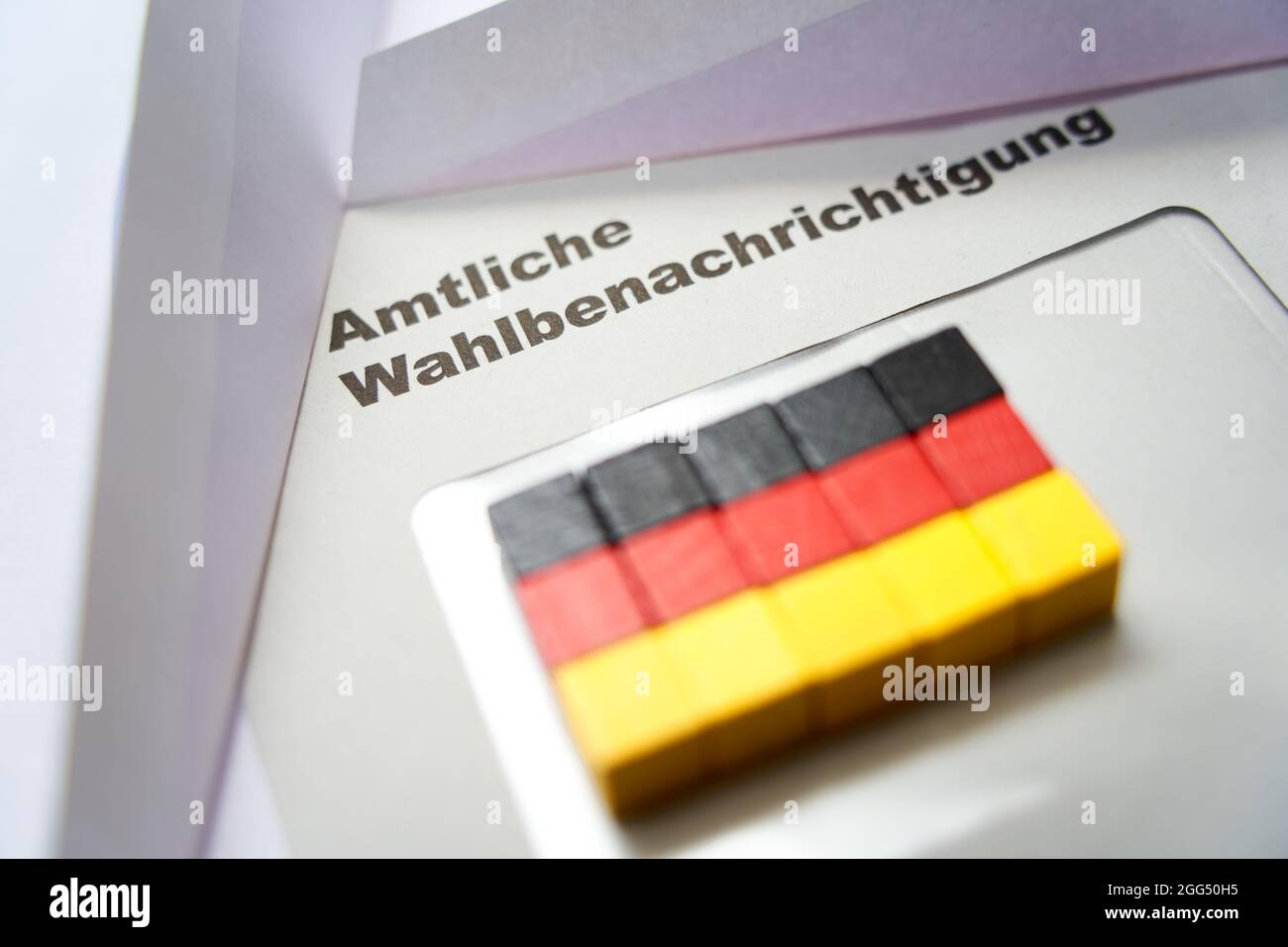 Lettere nere su busta bianca: Notifica ufficiale delle elezioni (in tedesco: Amtliche Wahlbenachrichtigung). Dadi in legno a forma di bandiera nazionale tedesca Foto Stock