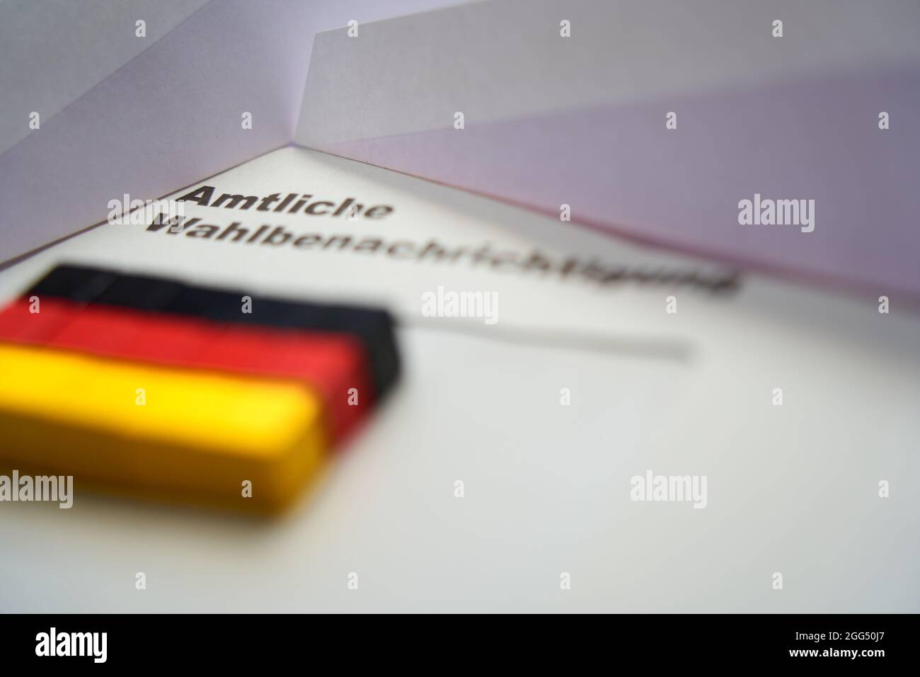 Lettere nere su busta bianca: Notifica ufficiale delle elezioni (in tedesco: Amtliche Wahlbenachrichtigung). Dadi in legno a forma di bandiera nazionale tedesca Foto Stock