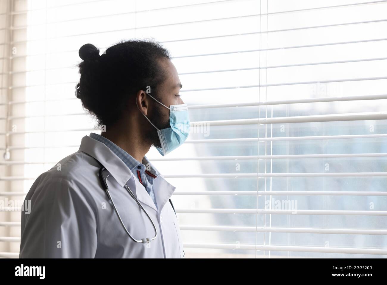 Il giovane medico afro-americano pensivo guarda a distanza. Foto Stock