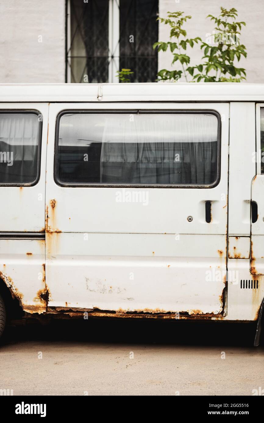 Vecchio furgone bianco arrugginito. Mini bus vecchio, arrugginito, danneggiato e abbandonato Foto Stock