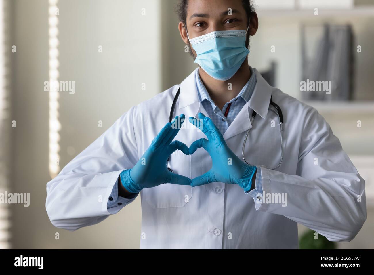 Felice medico africano GP giovane americano mostrando segno di cuore. Foto Stock
