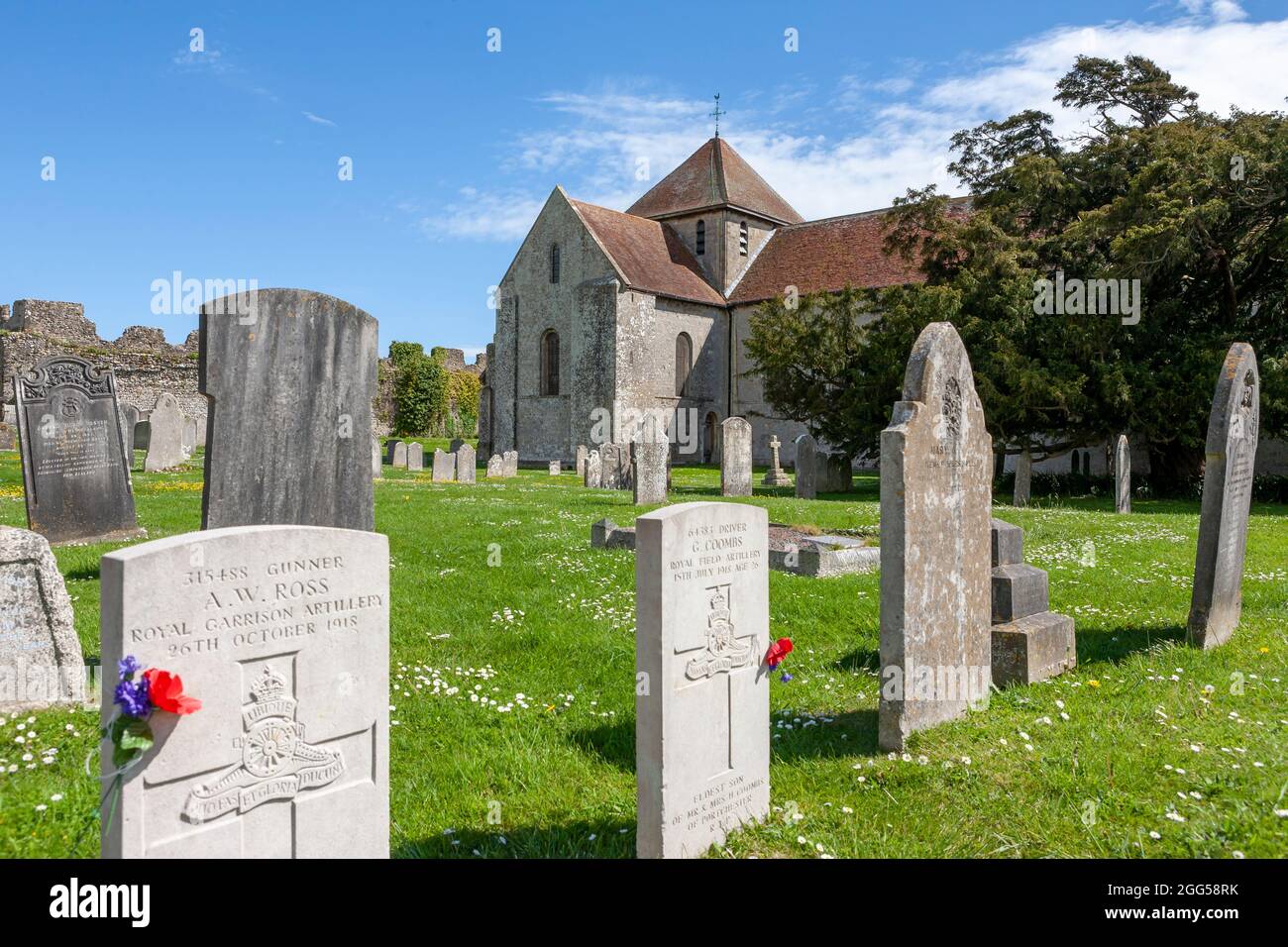 La chiesa 12 ° secolo di St Mary, all'interno del bailey esterno del Castello di Portchester: Cimitero e le mura vicine del forte romano originale, Hampshire, Regno Unito Foto Stock