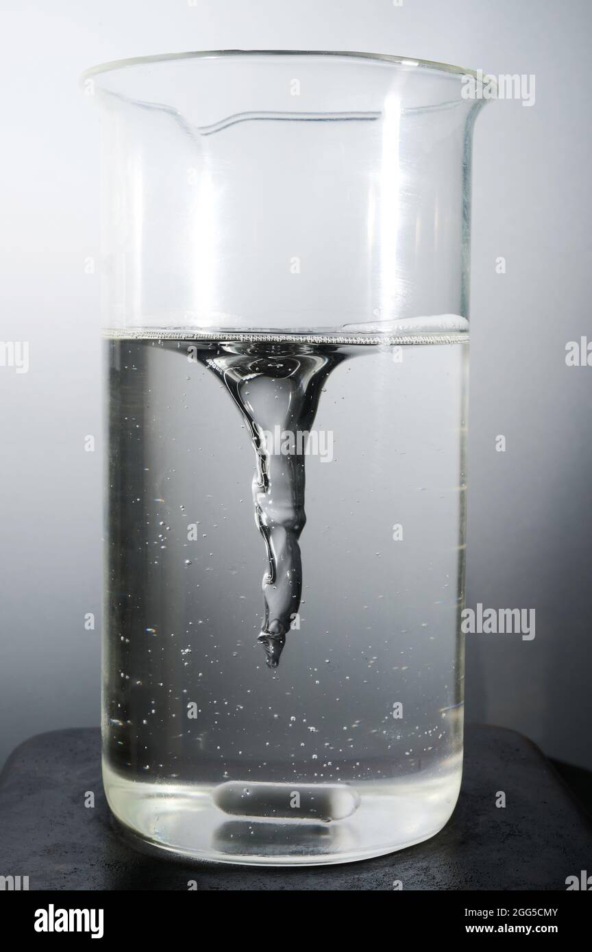 Processo di miscelazione della cera liquida in un pallone isolato su sfondo di studio Foto Stock