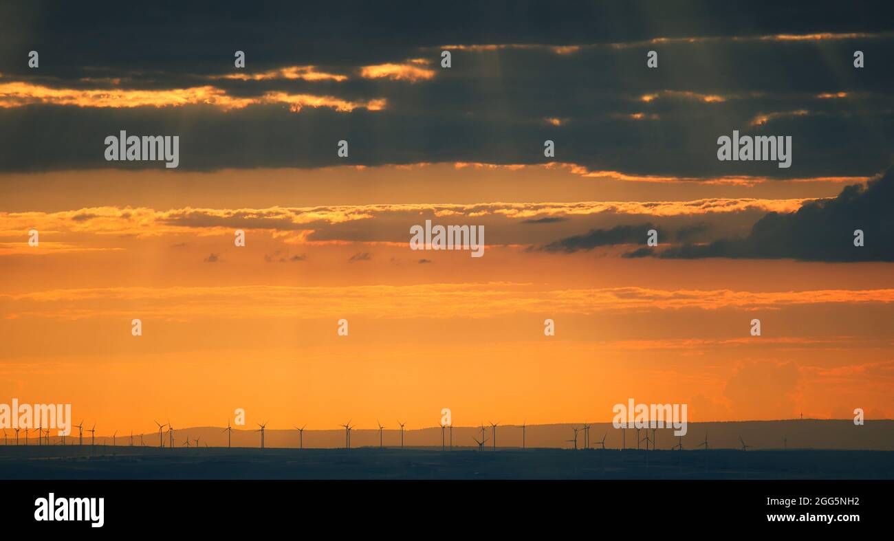 Turbine eoliche al tramonto con un cielo drammatico, Landscape in Germania, regione Reno-Neckar vicino Mannheim. Foto Stock