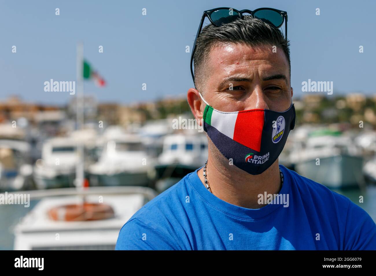 Attilio Lucia, rappresentante di Lampedusa della Lega, partito politico italiano di destra, populista ed euroscettico, fa un'intervista con la fotocamera il 28 agosto 2021, sul molo di Lampedusa, mentre allo stesso tempo i carabinieri aggregano centinaia di migranti per il trasporto in Sicilia. In un'eco del discorso di Trump "crimine e stupri", Lucia dice "non voglio generalizzare, ma non dimentichiamo che la maggior parte dei clandistini sono criminali". (Foto di John Rudoff/Sipa USA) Foto Stock