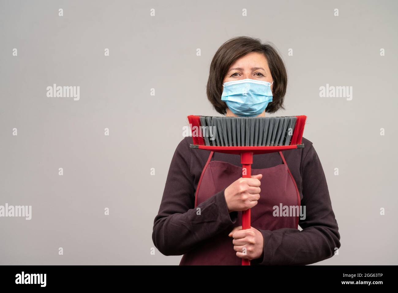 Una donna in una maschera chirurgica, un europeo di mezza età, una pulitrice, tiene un mop nelle sue mani. Il concetto di pulizia . Foto Stock