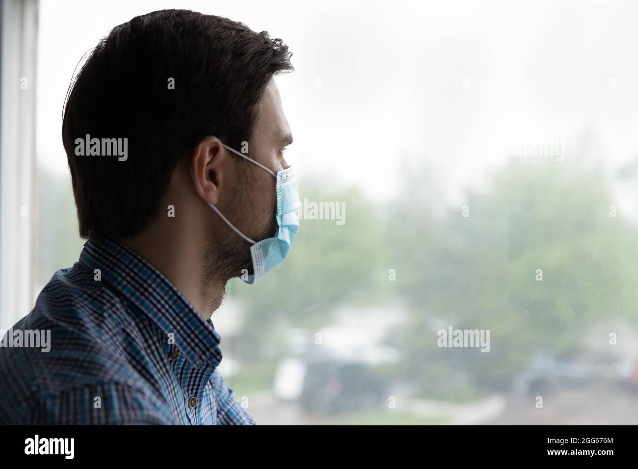 Uomo premuroso e depresso che guarda fuori dal finestrino con speranza Foto Stock