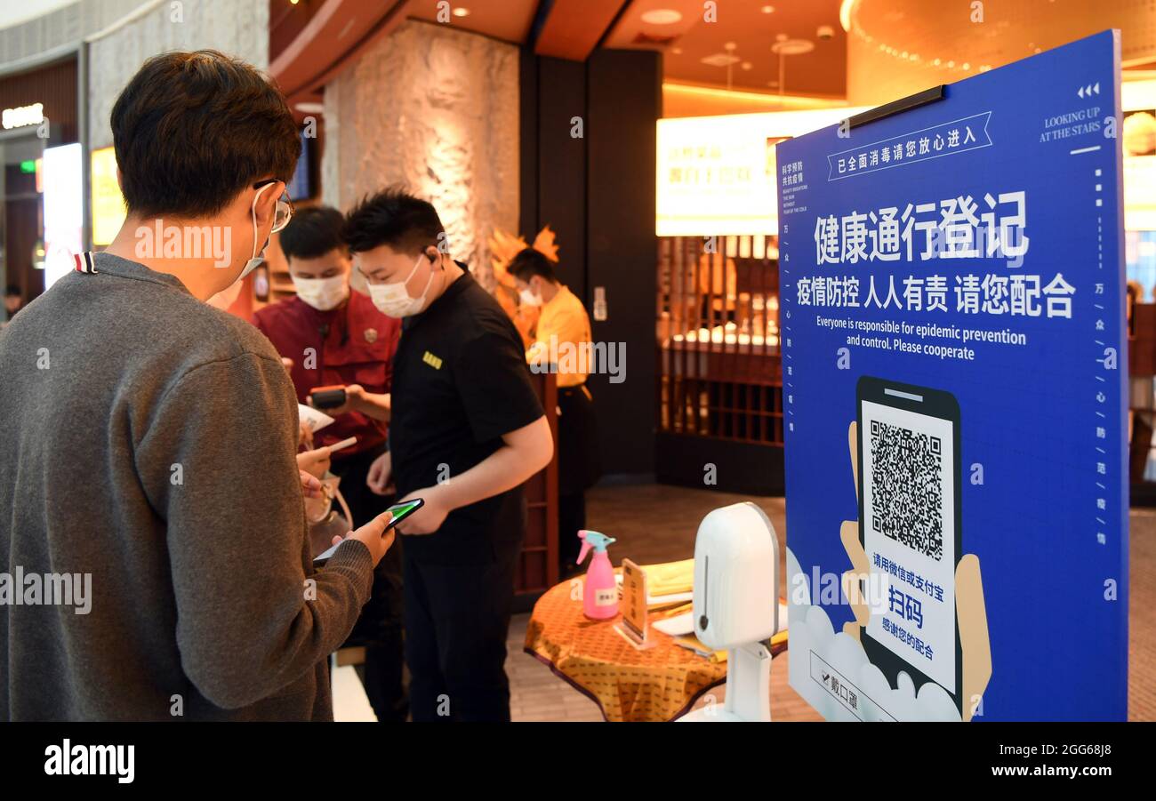 (210829) -- ZHENGZHOU, 29 agosto 2021 (Xinhua) -- i membri del personale aiutano i clienti a scansionare i codici QR quando entrano in un ristorante per garantire che i registri di viaggio di possibili casi COVID-19 possano essere rintracciabili a Zhengzhou, provincia centrale di Henan della Cina, 29 agosto 2021. Zhengzhou ha iniziato il sabato per consentire ai ristoranti di riprendere il servizio di ristorazione, richiedendo loro di condurre una disinfezione regolare, abbreviare le ore di pranzo e fornire chopstick e cucchiai di servizio. I clienti e i deliverymen da asporto sono invitati a sottoporsi alla scansione dei codici di temperatura e salute prima di entrare nei ristoranti. Città di Zhengzhou cancellata Foto Stock