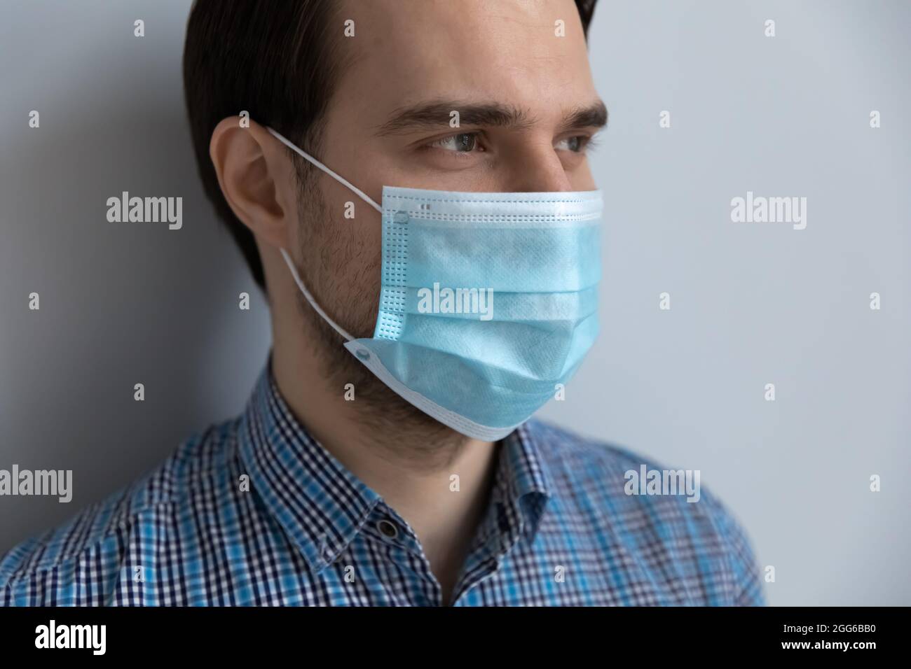 Primo piano di uomo millenario con maschera medica blu pallido Foto Stock