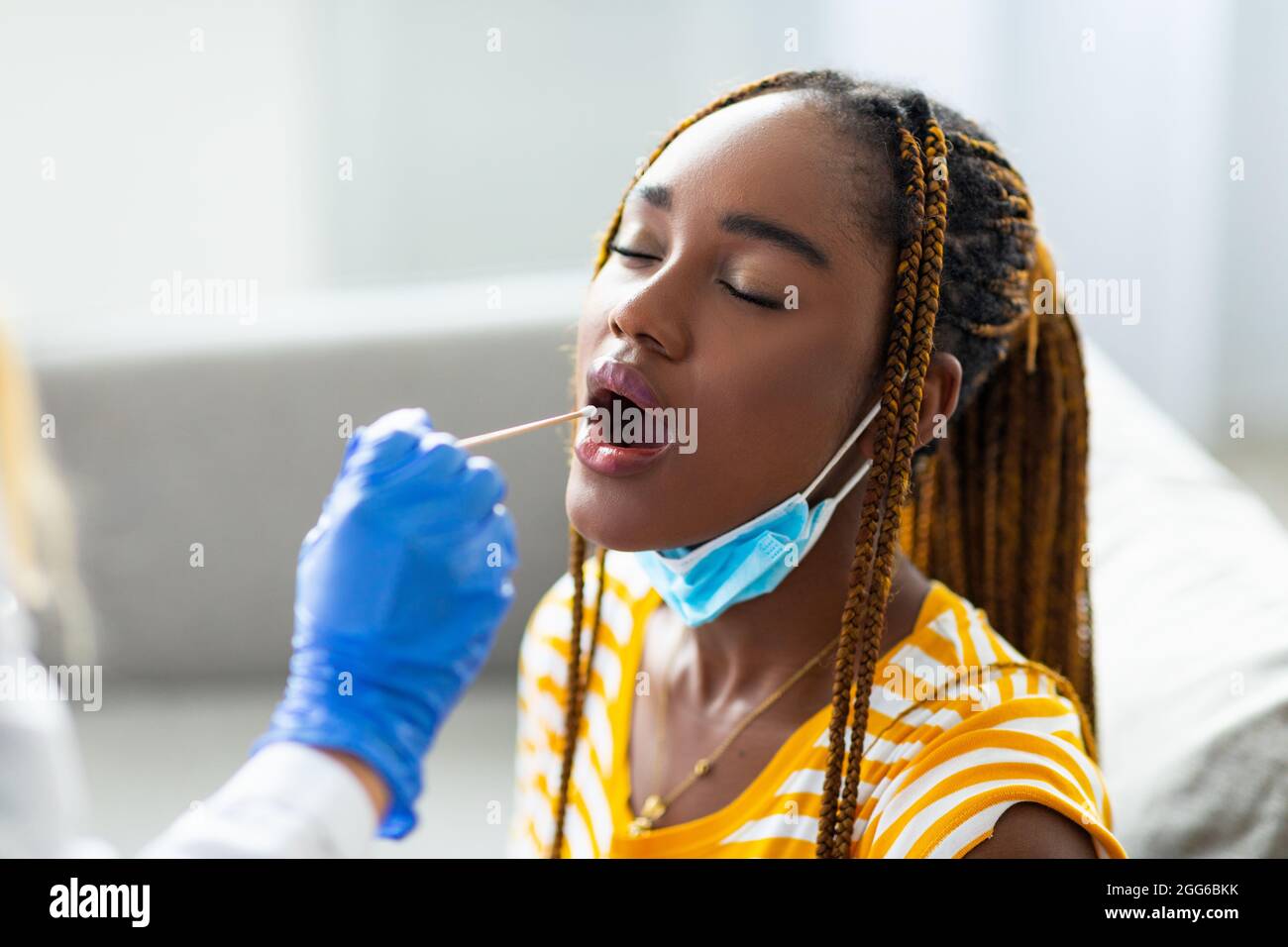 Donna nera che ottiene il test orale del tampone del coronavirus a casa Foto Stock