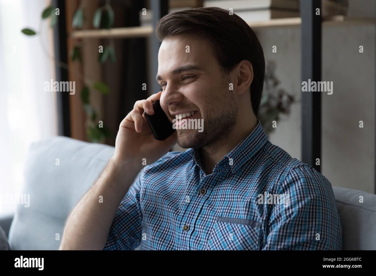 Ragazzo felice millenario godendo piacevole conversazione telefonica Foto Stock