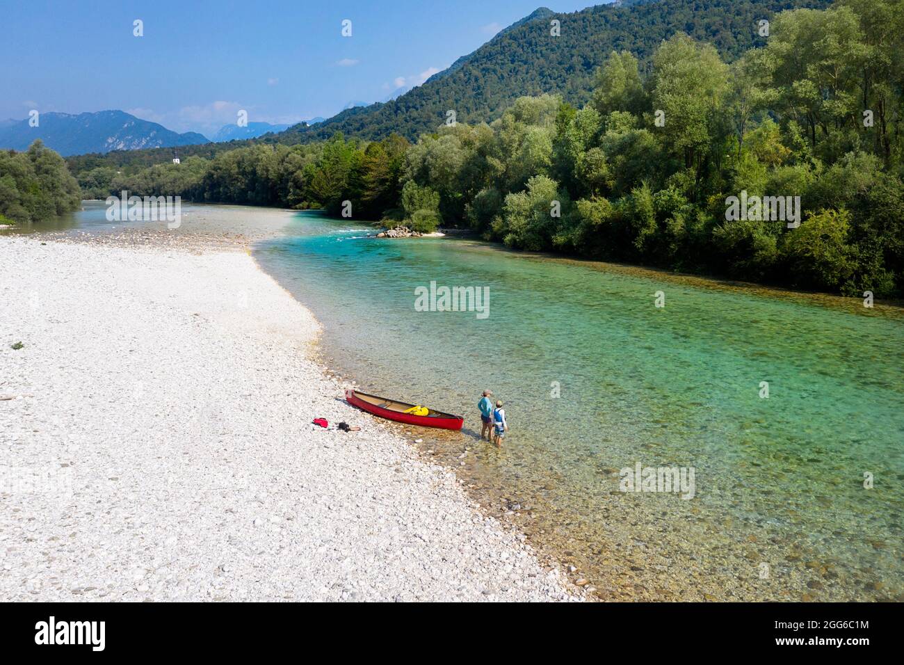 Veduta aerea di madre e figlio in piedi in acque poco profonde da una canoa rossa sul fiume Soca vicino a Tolmin, Slovenia Foto Stock