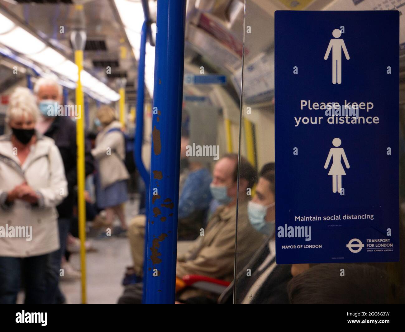 Treno della metropolitana di Londra con si prega di mantenere il vostro segnale di distanza durante il Covid Coronavirus Pandemic, con i passeggeri che indossano maschere di protezione personale PPE Foto Stock