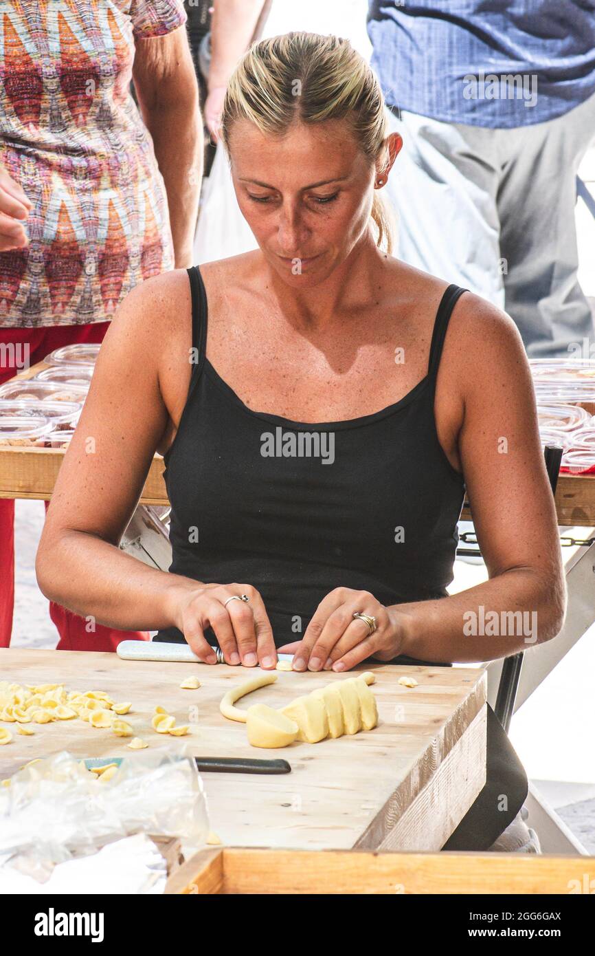 Bella donna locale che si prepara nella strada del centro storico di Bari orecchiette fresche o orecchietta, fatta con grano duro e acqua, pasta fatta a mano Foto Stock