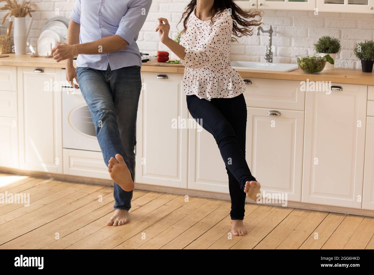 Concentratevi sulle gambe a piedi nudi della giovane coppia felice famiglia che balla. Foto Stock