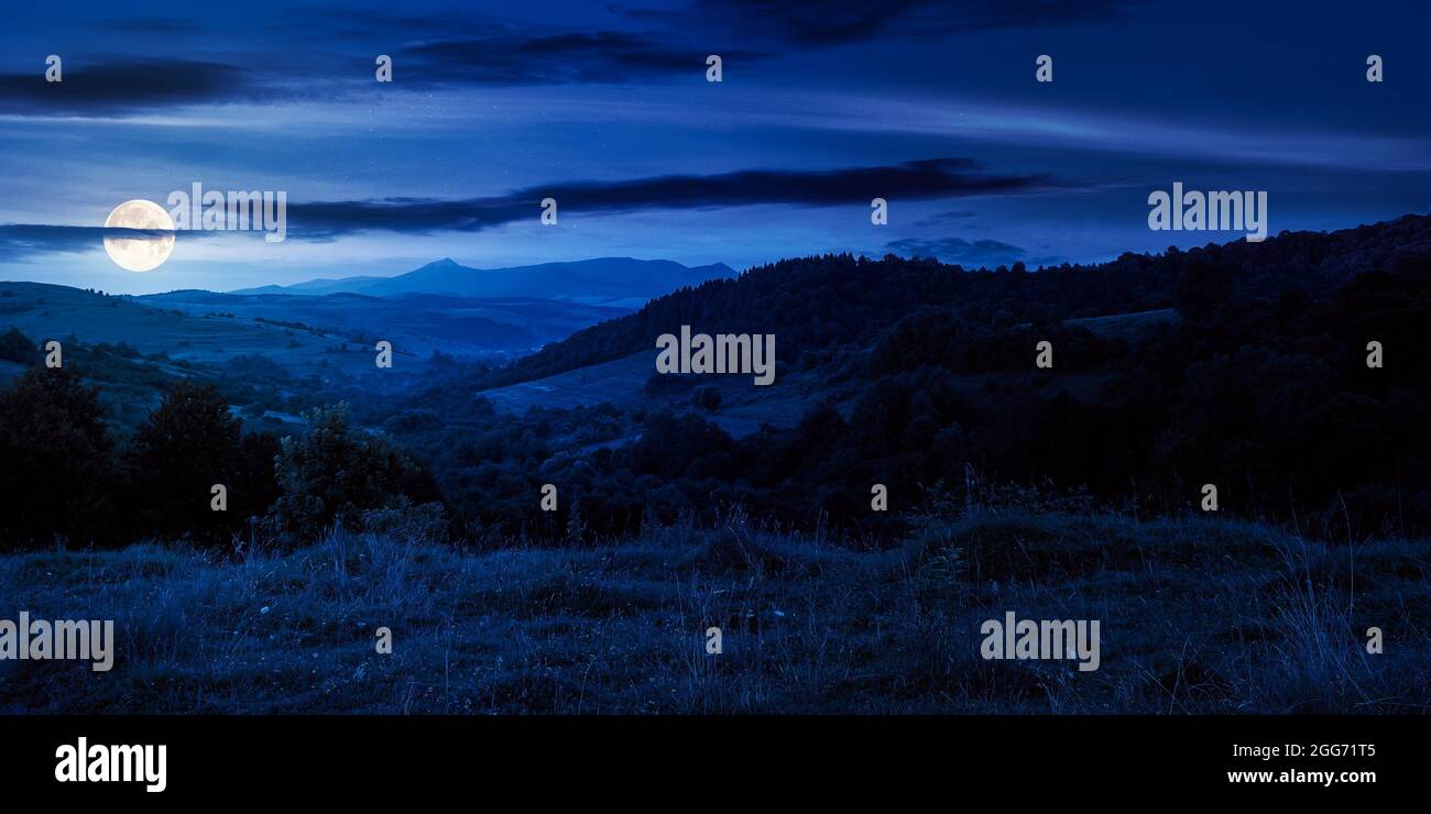 paesaggio montagnoso di notte. pascoli e campi rurali vicino alla foresta sulle colline. bel paesaggio naturale all'inizio dell'autunno con le nuvole Foto Stock