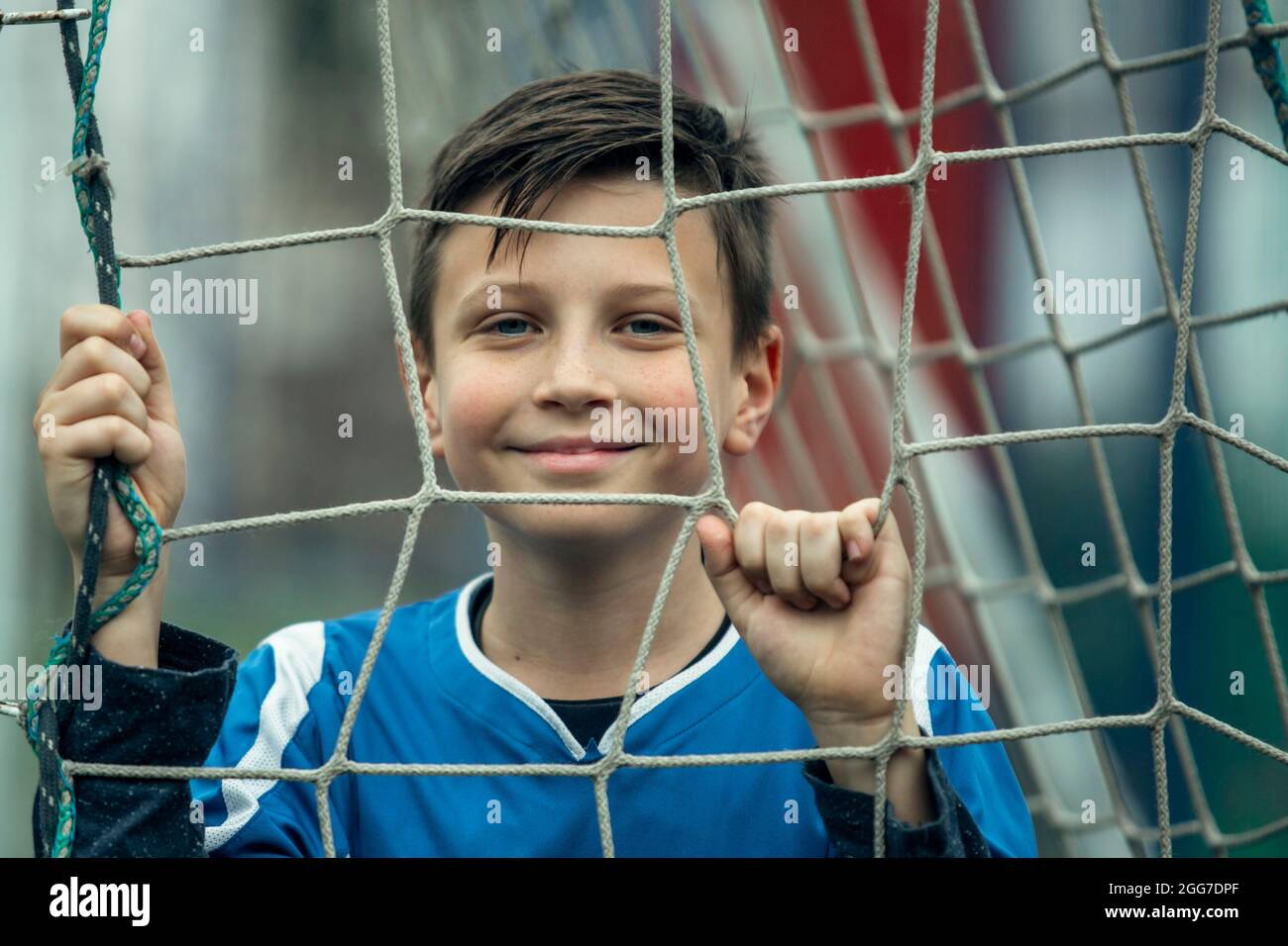 Ritratto del ragazzo giocatore vicino al cancello sul campo di calcio. Foto Stock
