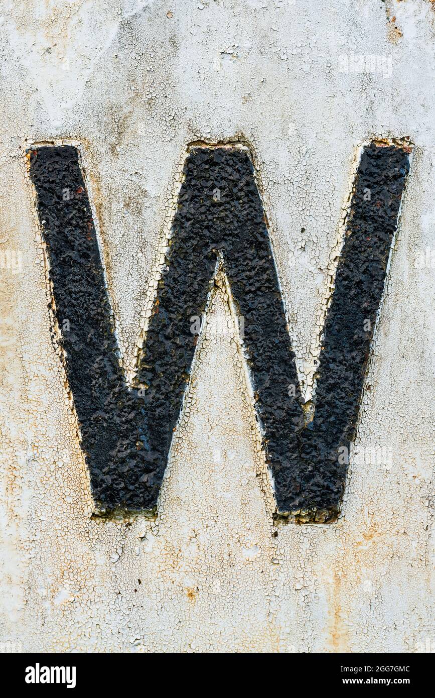 Lettera W ad alta texture in vernice nera peeling su sfondo bianco Foto Stock