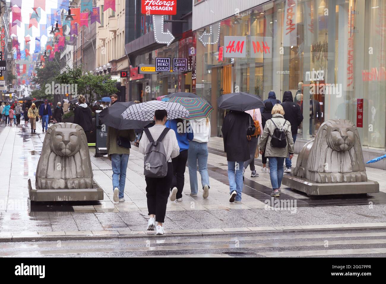 Stoccolma, Svezia - 16 agosto 2021: Persone alla strada pedonale Drottninggatan nel quartiere del centro con ombrelloni durante la pioggia. Foto Stock