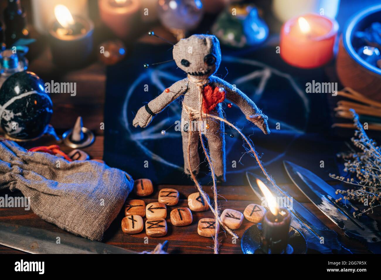 Bambola Voodoo tra candele bruciate e oggetti rituali magici per rito esoterico sinistro e scuro. Foto Stock