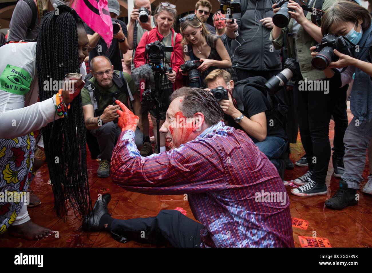 Londra, Regno Unito. 27 agosto 2021. Un attivista della ribellione dell'estinzione vestito da finanziere coperto di sangue falso si occupa di una disputa razzista con Marvina Newton, fondatore di United for Black Lives, in Paternoster Square, a seguito di una marcia Blood Money nella città di Londra. Extinction Rebellion intendevano evidenziare le istituzioni finanziarie che finanziavano progetti sui combustibili fossili, soprattutto nel Sud del mondo, così come gli studi legali e le istituzioni che li agevolano, mentre chiedevano al governo britannico di cessare tutti i nuovi investimenti sui combustibili fossili con effetto immediato. Credit: Mark Kerrison/Alamy Live News Foto Stock