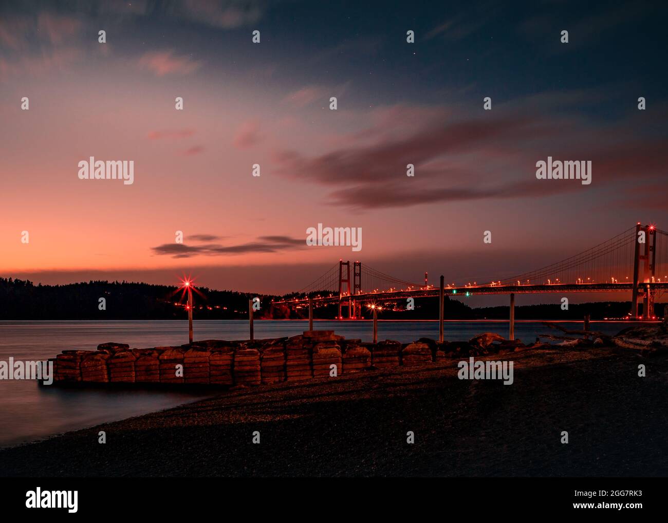 Una foto della linea costiera a Hidden Beach Park a Tacoma, Washington. L'immagine è una lunga esposizione al tramonto di fronte al ponte Tacoma Narrows Foto Stock