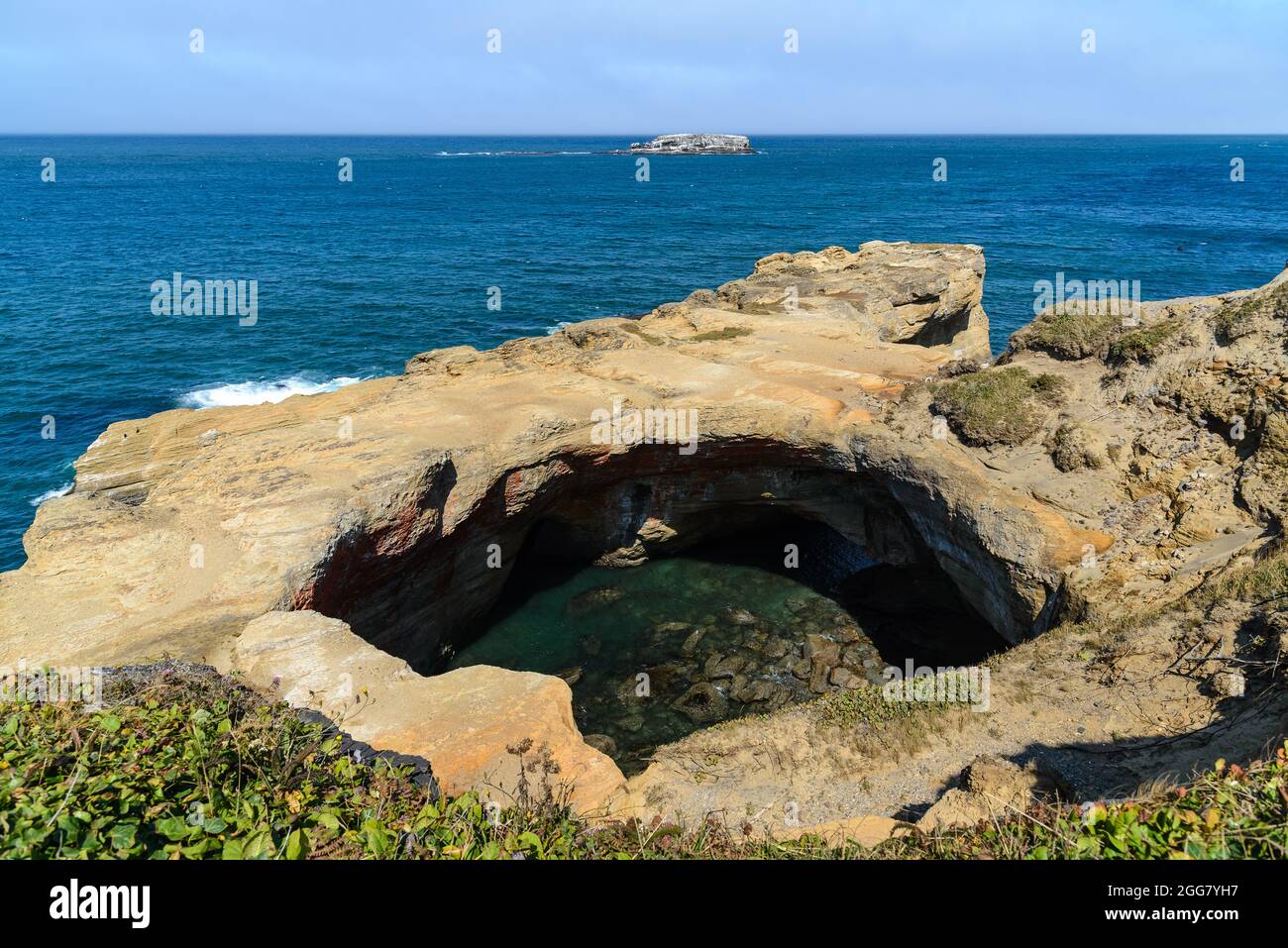 Ondeggia la formazione di roccia intagliata presso l'area naturale statale Devils Punchbowl sulla costa dell'Oregon centrale, USA. Foto Stock