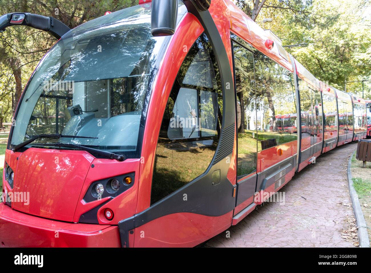 Tram rosso sulla strada alberata. Concetto di trasporto pubblico ecologico Foto Stock
