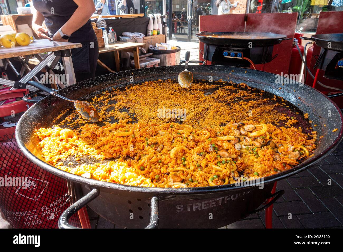 Una bancarella di Street food a Windsor, Regno Unito, che vende paella cotta in grandi padelle su bruciatori a gas. Foto Stock