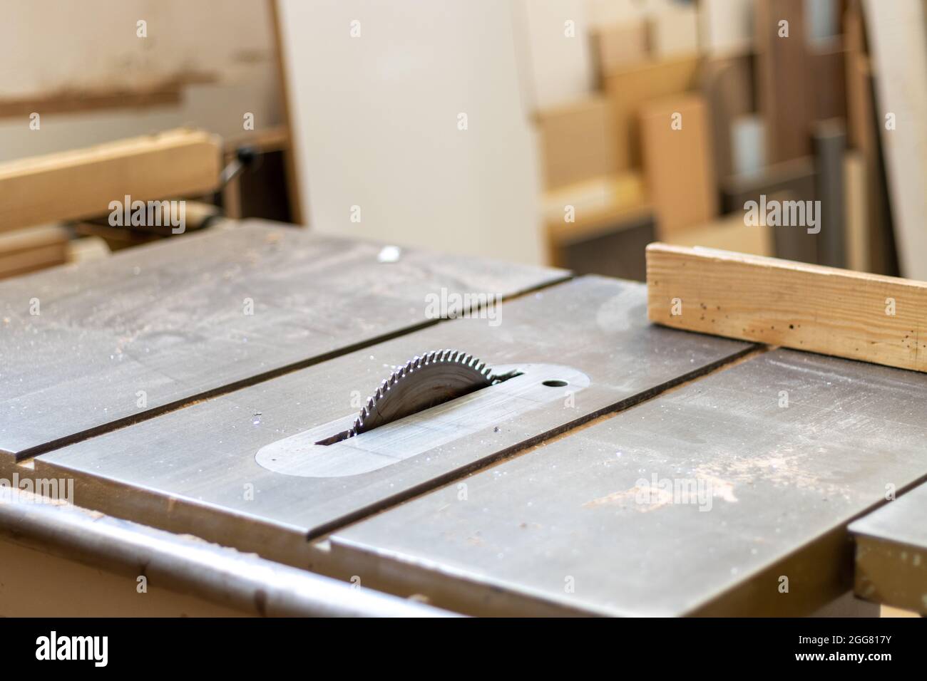 Il falegname sta tagliando il legno con una macchina elettrica industriale per il taglio del legno per la produzione di mobili in officina Foto Stock