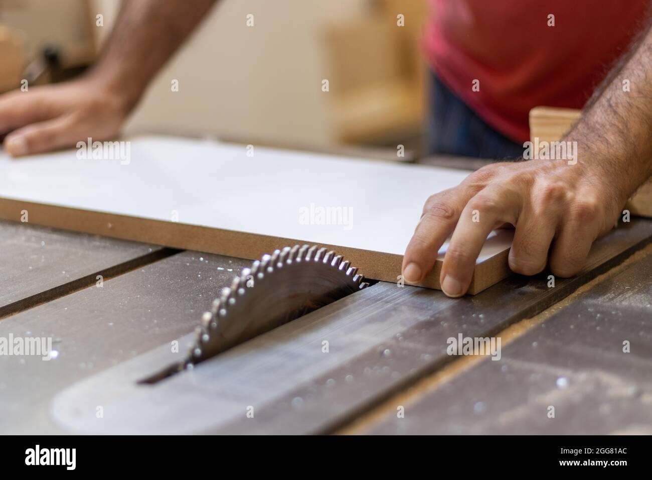 Il falegname sta tagliando il legno con una macchina elettrica industriale per il taglio del legno per la produzione di mobili in officina Foto Stock