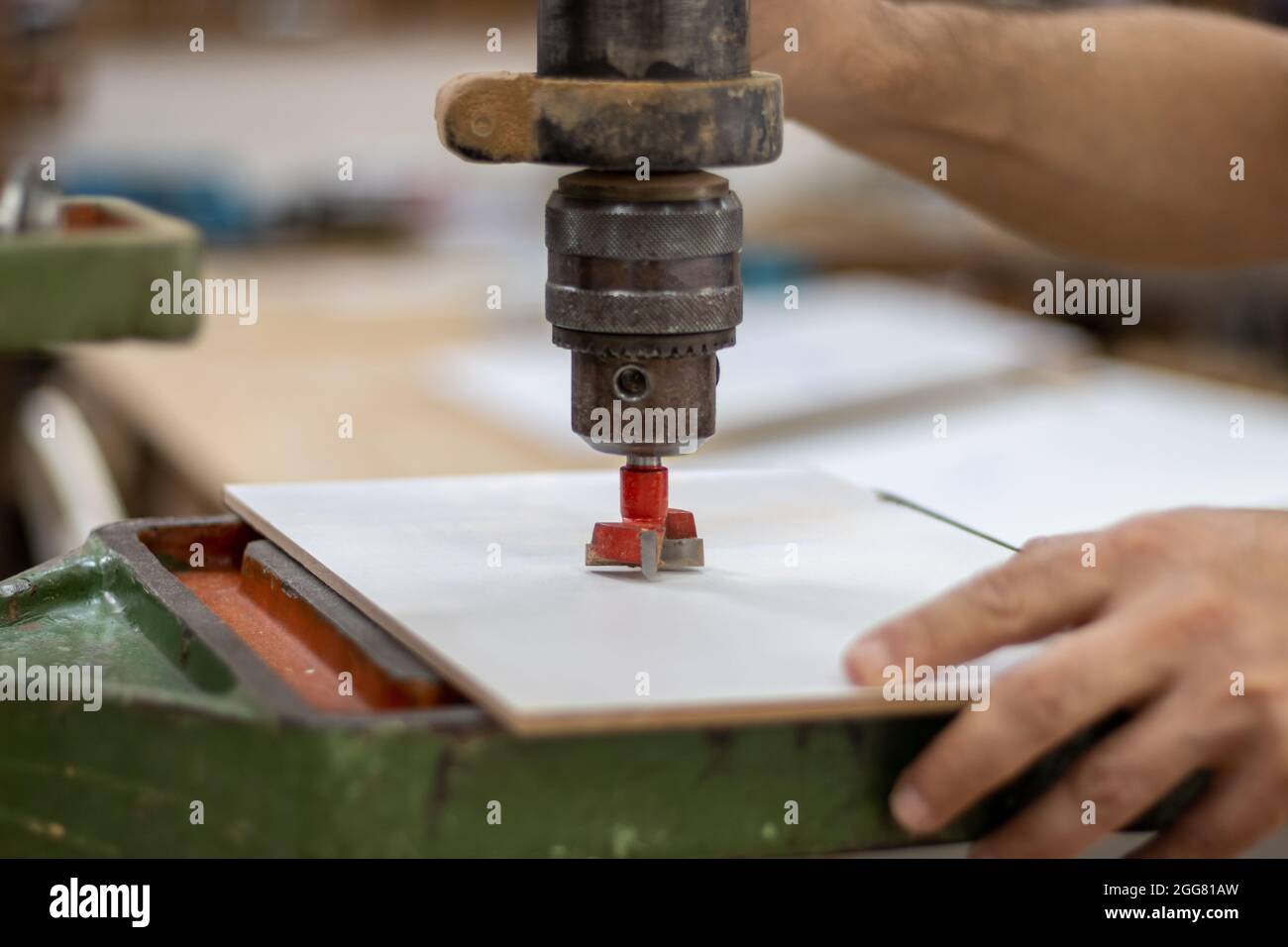 Il falegname sta tagliando il legno con una macchina elettrica industriale per il taglio del legno per la produzione di mobili in officina Foto Stock