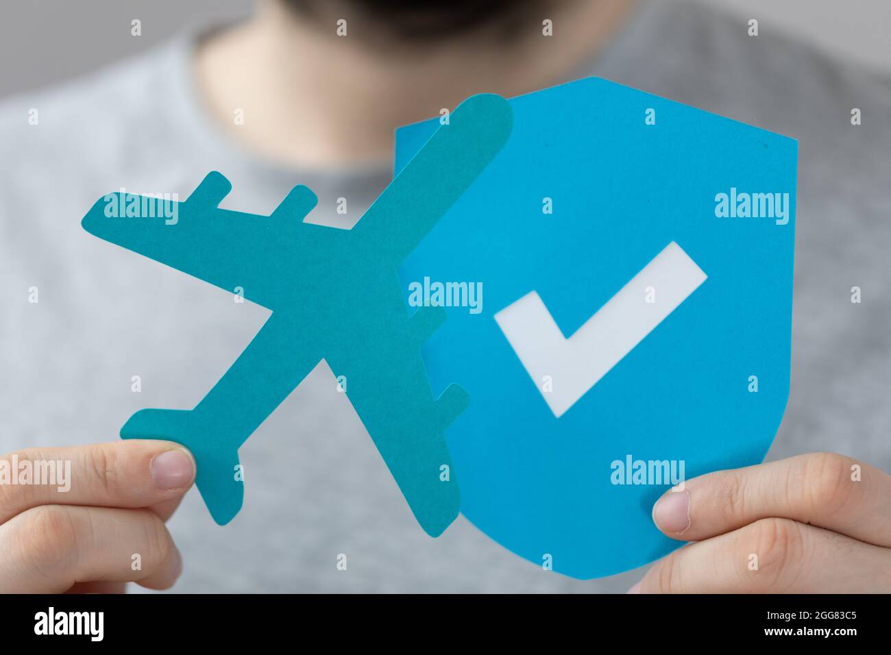 Persona che tiene un aeroplano e scudo icone papercut - concetto di volo sicuro Foto Stock