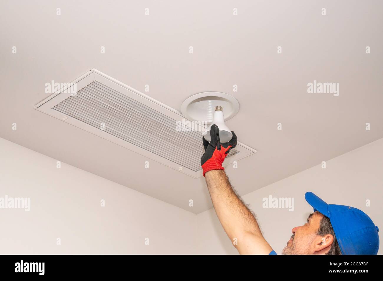 Un uomo che cambia un proiettore in alto all'interno Foto Stock