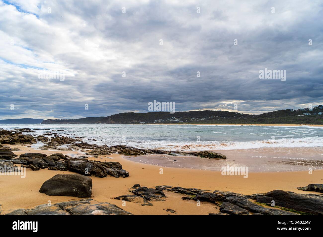 Putty Beach, Central Coast, NSW, Australia in una giornata di tempesta selvaggia con rocce in primo piano Foto Stock