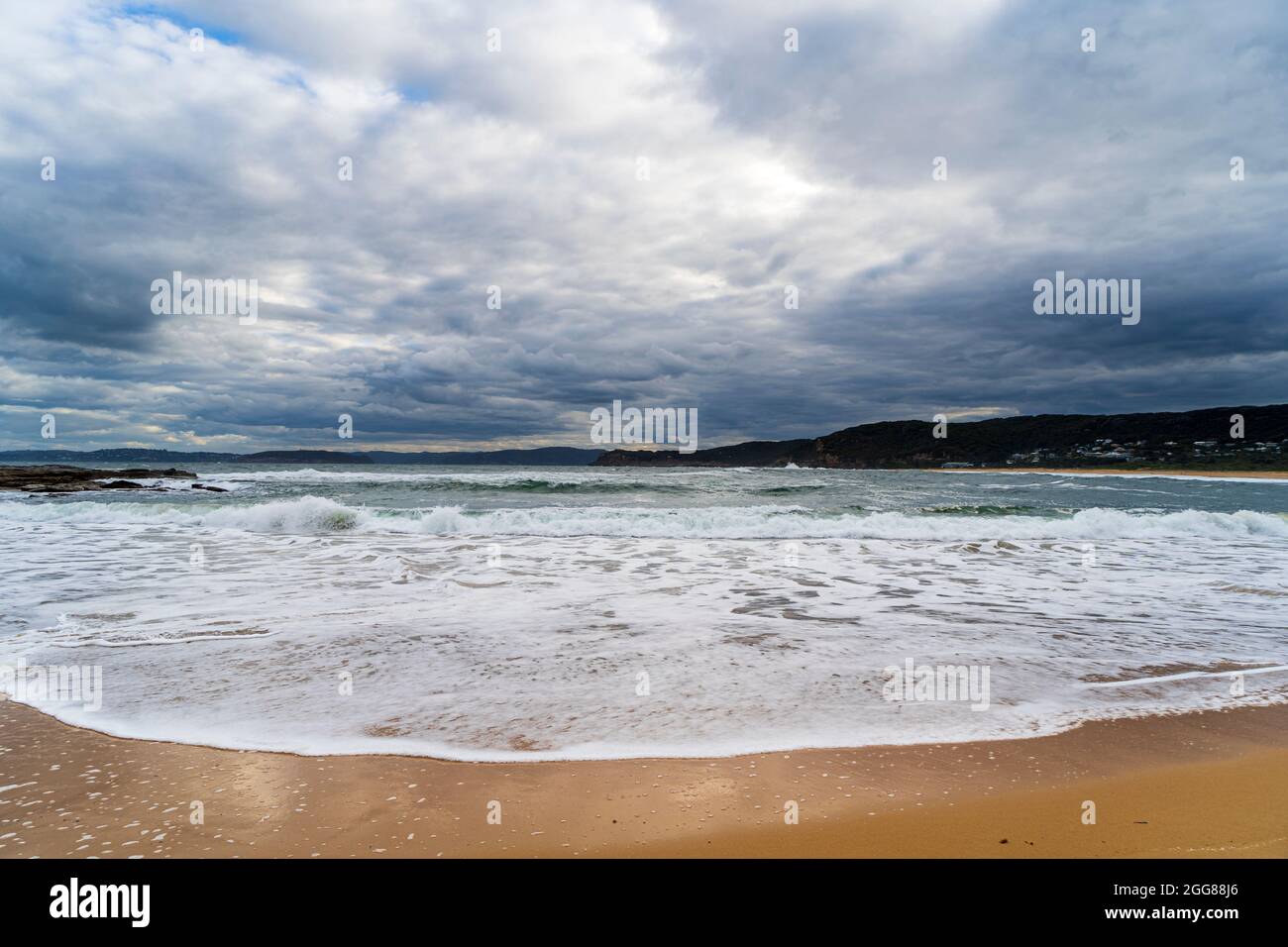 Putty Beach, Central Coast, NSW, Australia in una giornata di tempesta selvaggia con un ampio scatto di onde schiumose sulla sabbia Foto Stock