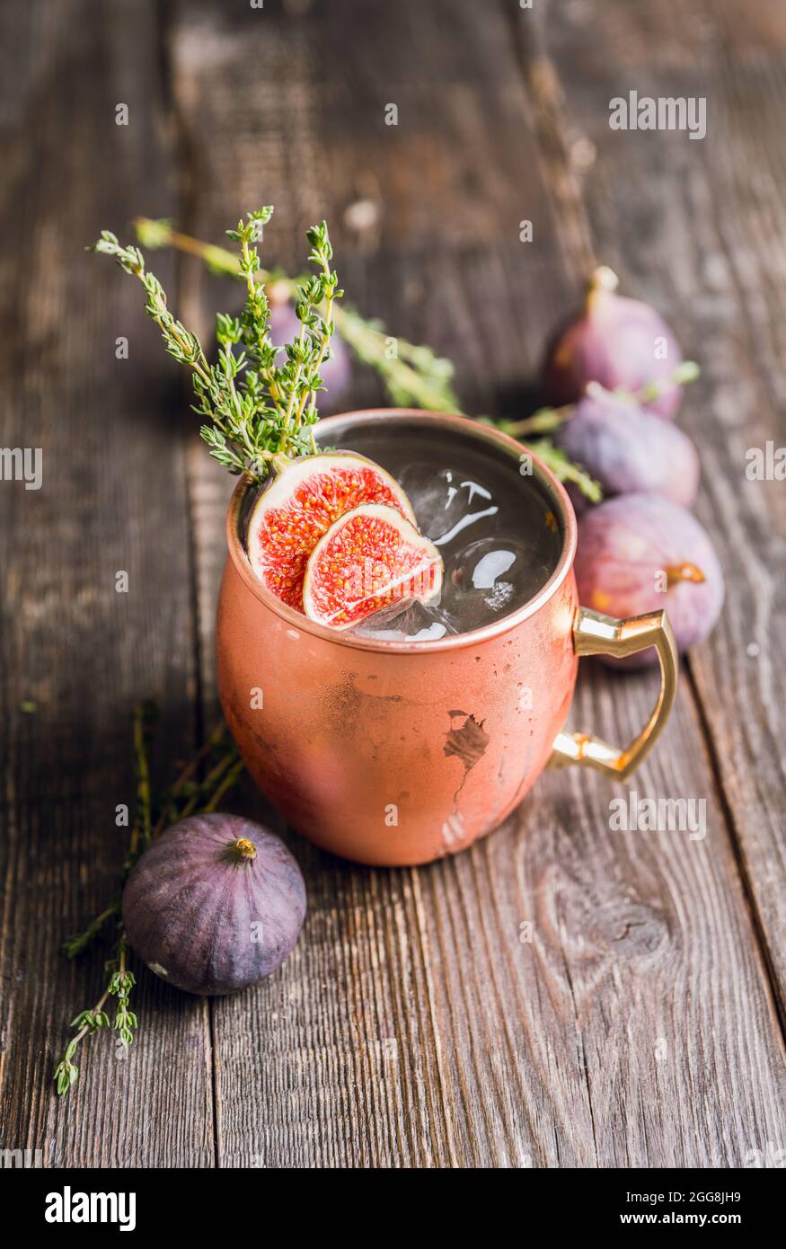 Cocktail mulo di Mosca con fichi e timo sullo sfondo rustico. Messa a fuoco selettiva. Profondità di campo poco profonda. Foto Stock