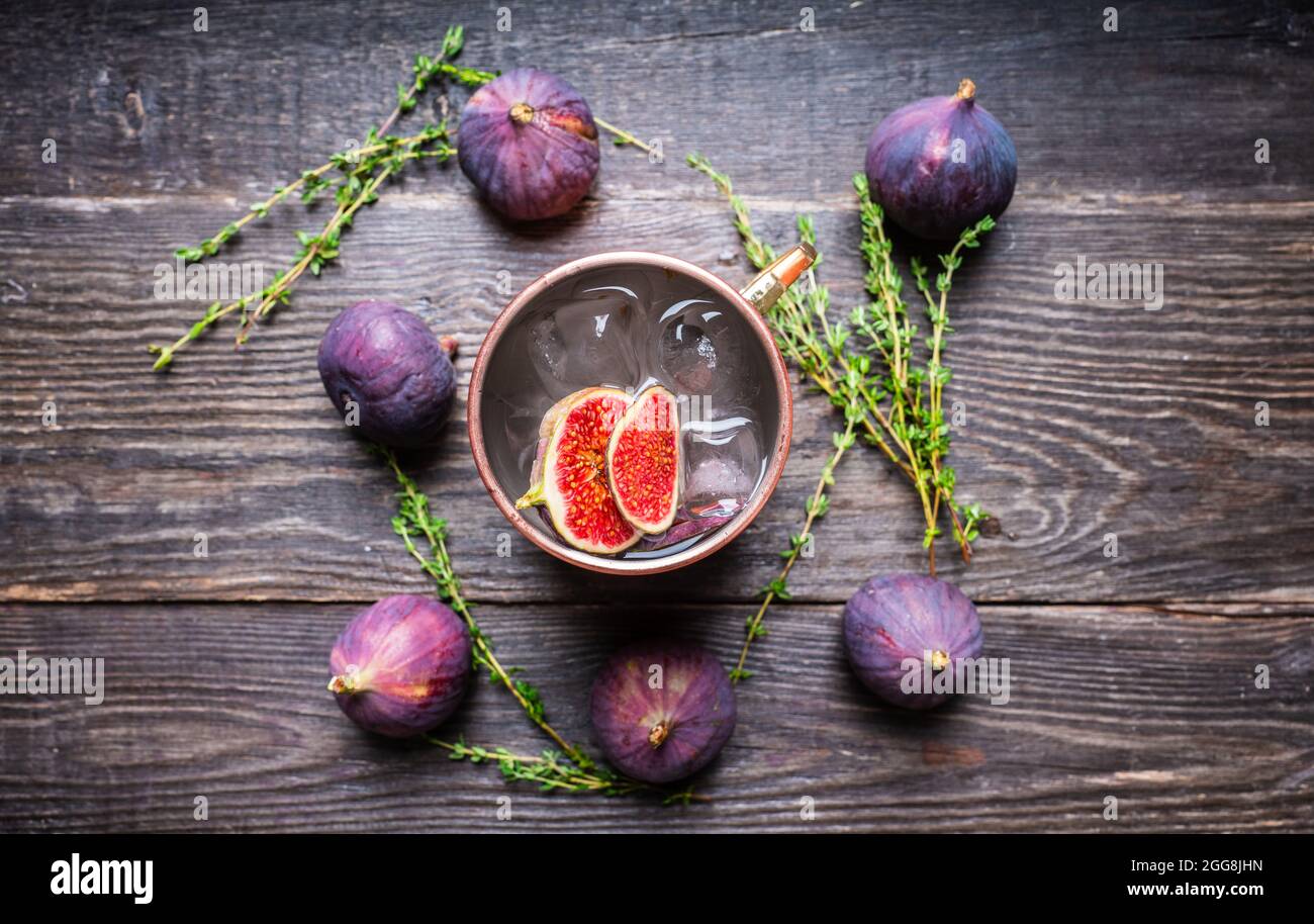 Cocktail mulo di Mosca con fichi e timo sullo sfondo rustico. Messa a fuoco selettiva. Profondità di campo poco profonda. Foto Stock