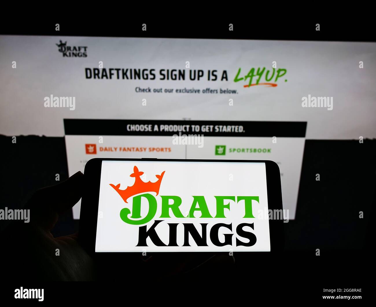 Persona che detiene smartphone con il logo della società di scommesse sportive statunitense DraftKings Inc. Sullo schermo di fronte al sito web. Mettere a fuoco sul display del telefono. Foto Stock