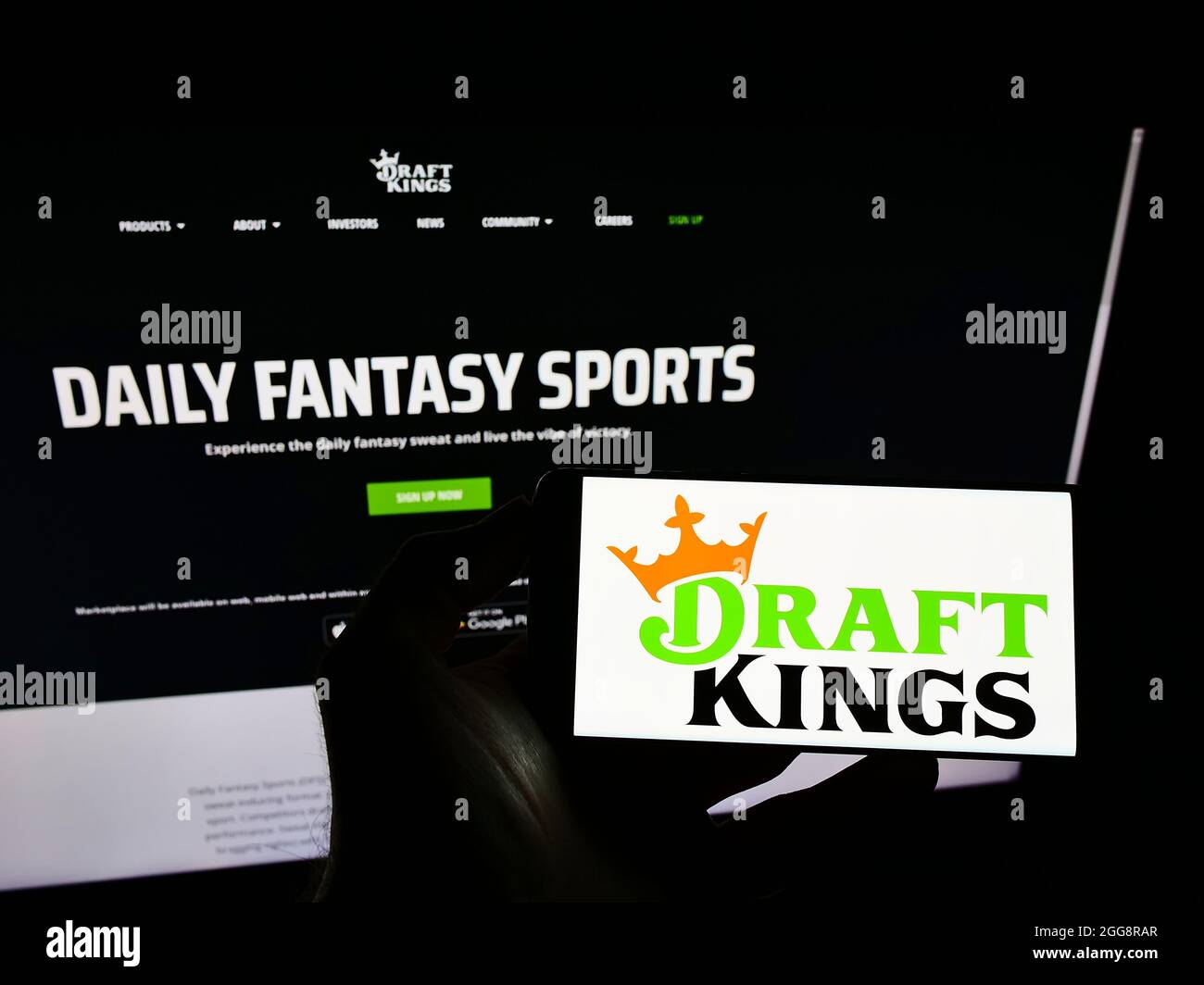 Persona che detiene il cellulare con il logo della società di scommesse sportive americane DraftKings Inc. Sullo schermo di fronte al sito web. Mettere a fuoco sul display del telefono. Foto Stock