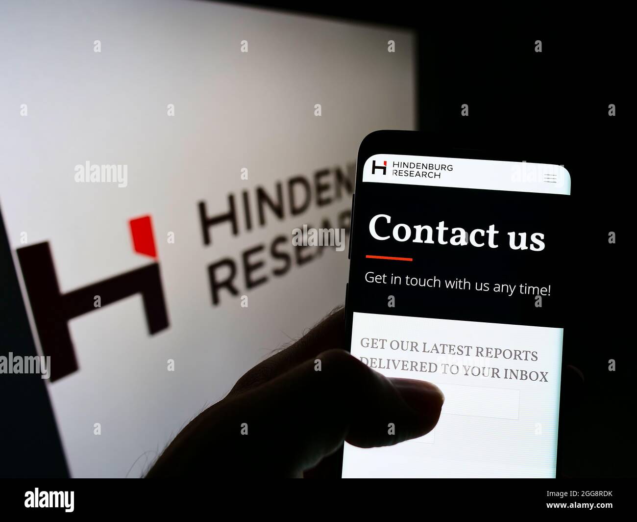 Persona che detiene il cellulare con il sito web della società di investimento Hindenburg Research LLC sullo schermo di fronte al logo. Concentrarsi sul centro del display del telefono. Foto Stock