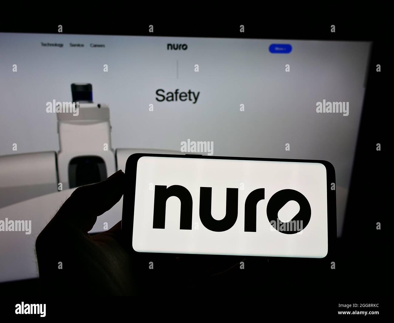 Persona che tiene uno smartphone con il logo della società di guida autonoma americana Nuro Inc. Sullo schermo di fronte al sito Web. Mettere a fuoco sul display del telefono. Foto Stock