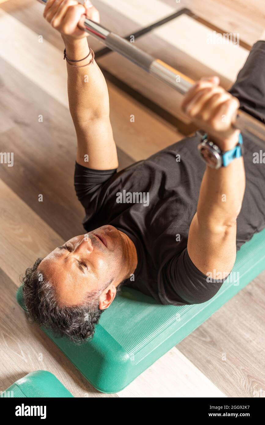Vista ritagliata di un uomo adulto che fa la pressa della panca sul punto in palestra Foto Stock