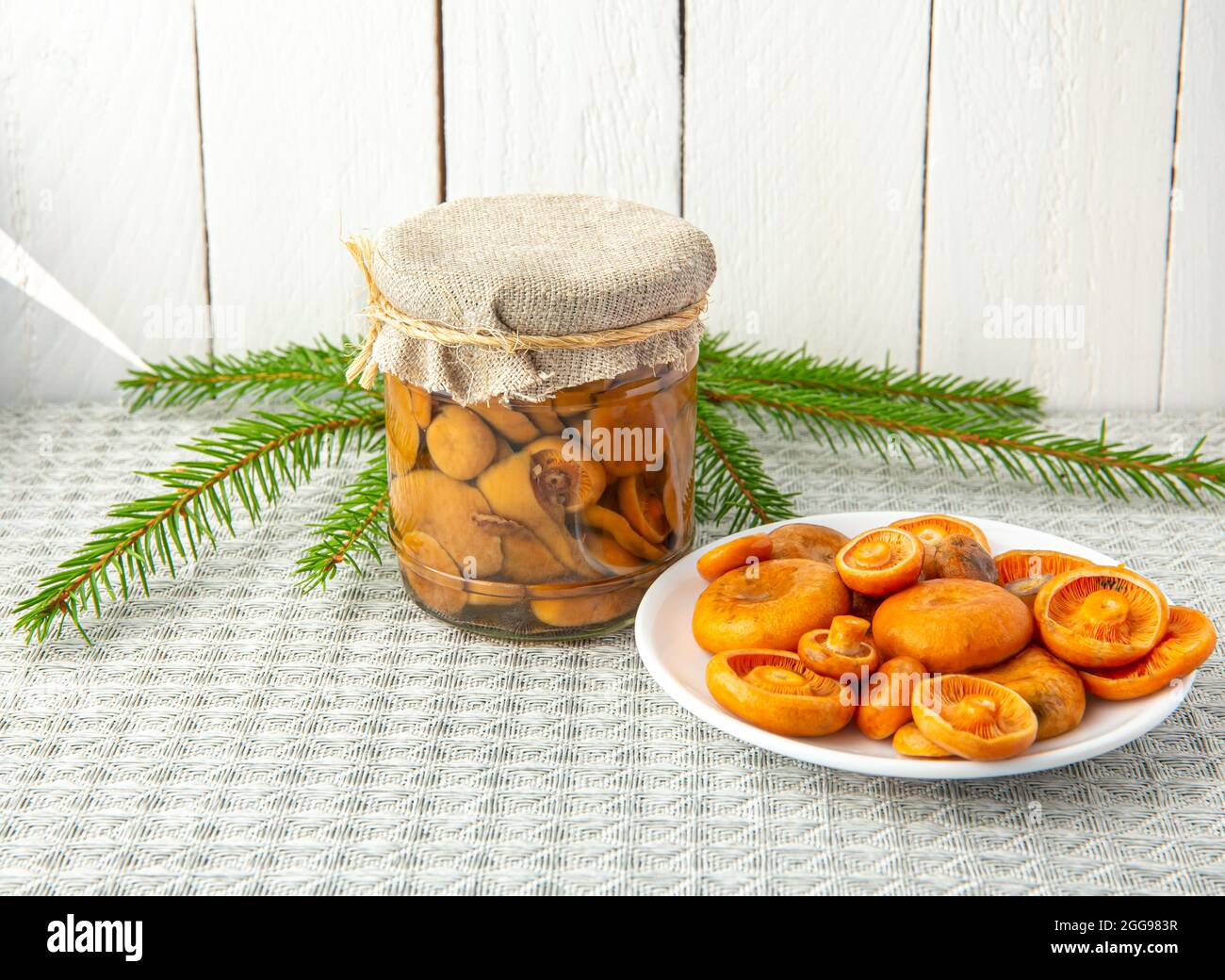 Funghi marinati aranciata o falso zafferano milkcap, Lactarius deterrimus in un vaso di vetro e funghi freschi raccolti sul piatto. Foto Stock