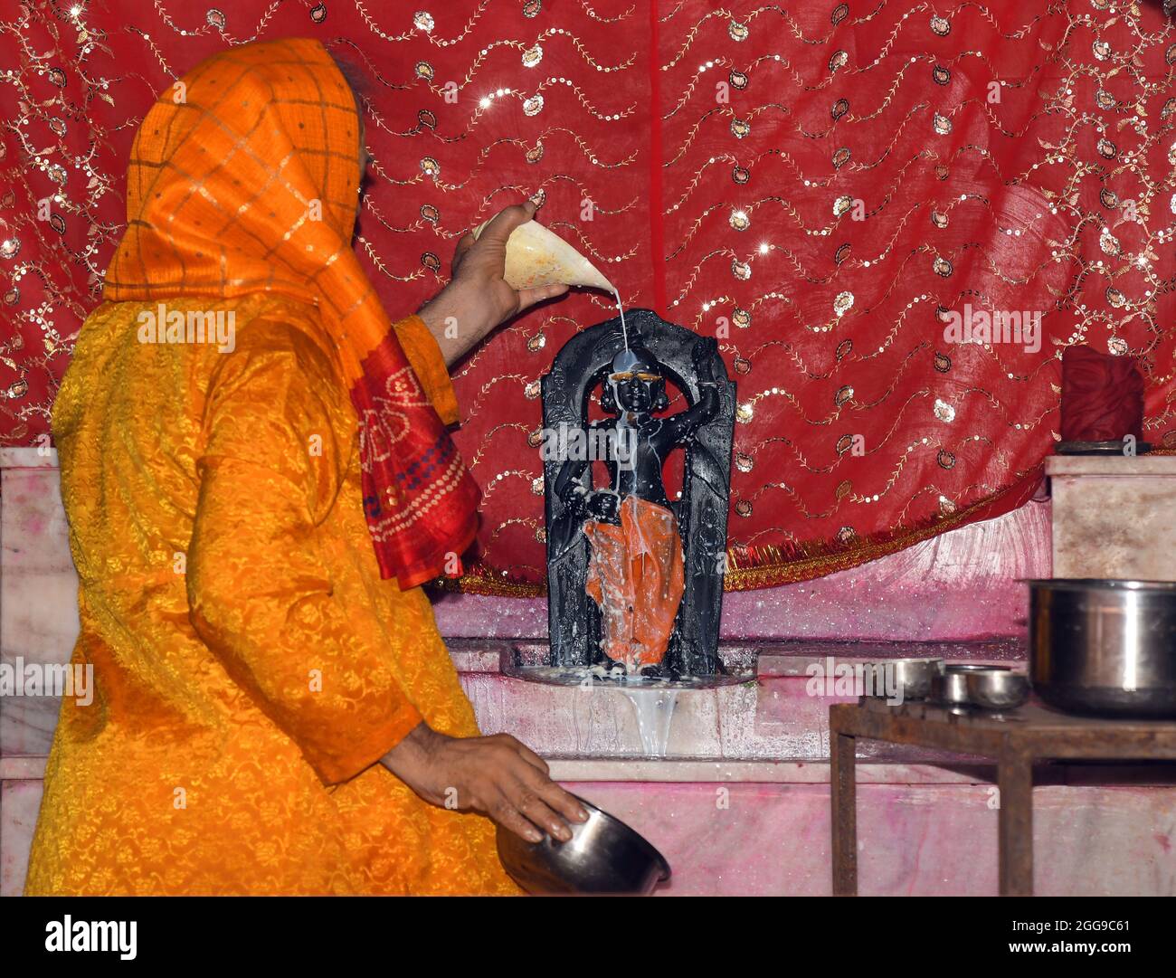 Beawar, Rajasthan, India, 30 agosto 2021: Il sacerdote indù versa il latte sull'idolo del Signore Krishna come parte dei rituali di Abhishek in occasione del festival di Janmashtami al tempio di Govardhan Nath a Beawar. Janmashtami festival che segna il compleanno di Dio indù Krishna, celebrato su Ashtami (ottavo giorno) del Krishna Paksha (quindicina scura) del mese santo di Bhadrapad (agosto-settembre) in calendario indù. Credit: Sumit Saraswat/Alamy Live News Foto Stock