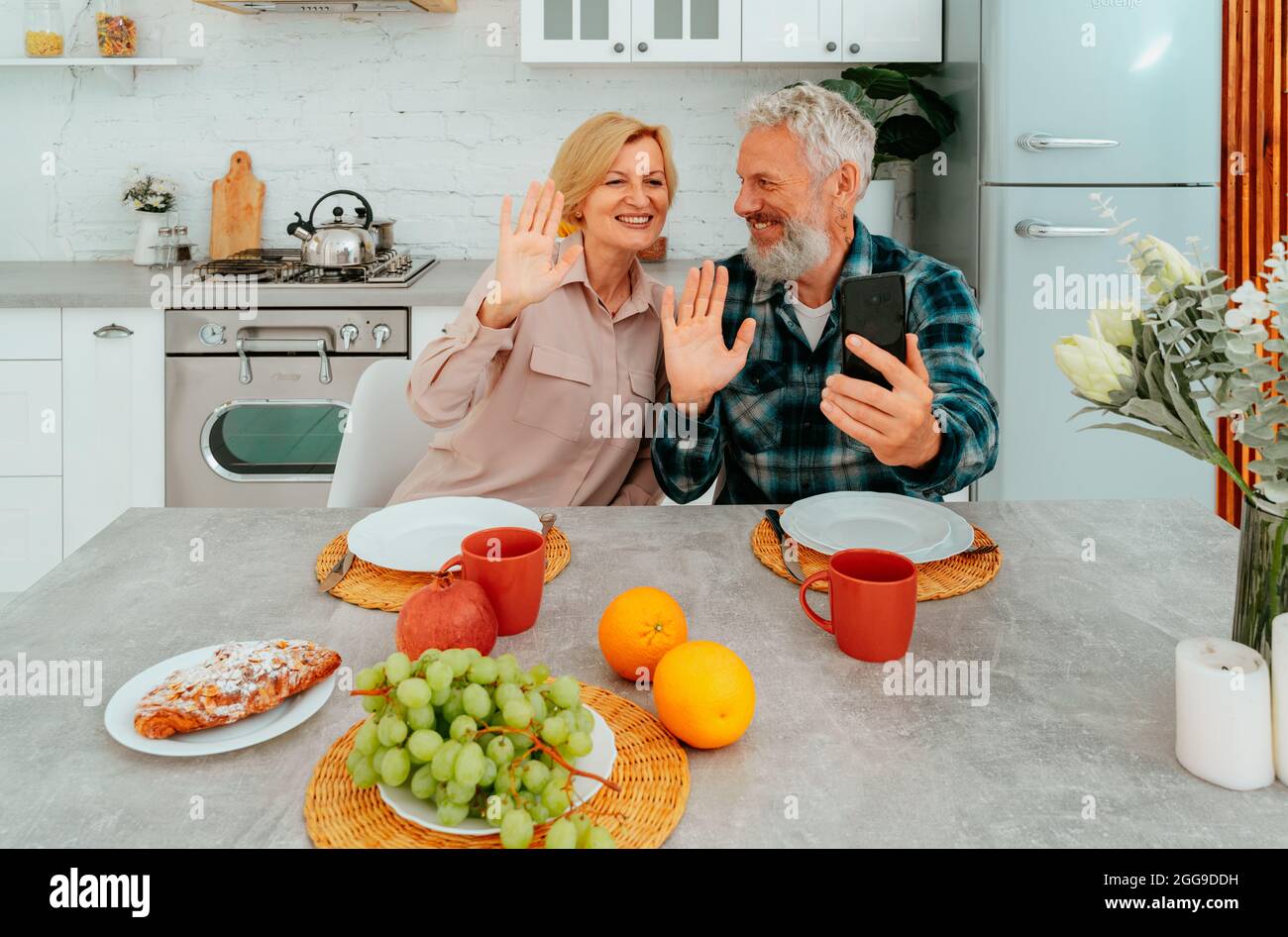 la coppia saluta gli amici con una videochiamata durante la colazione Foto Stock