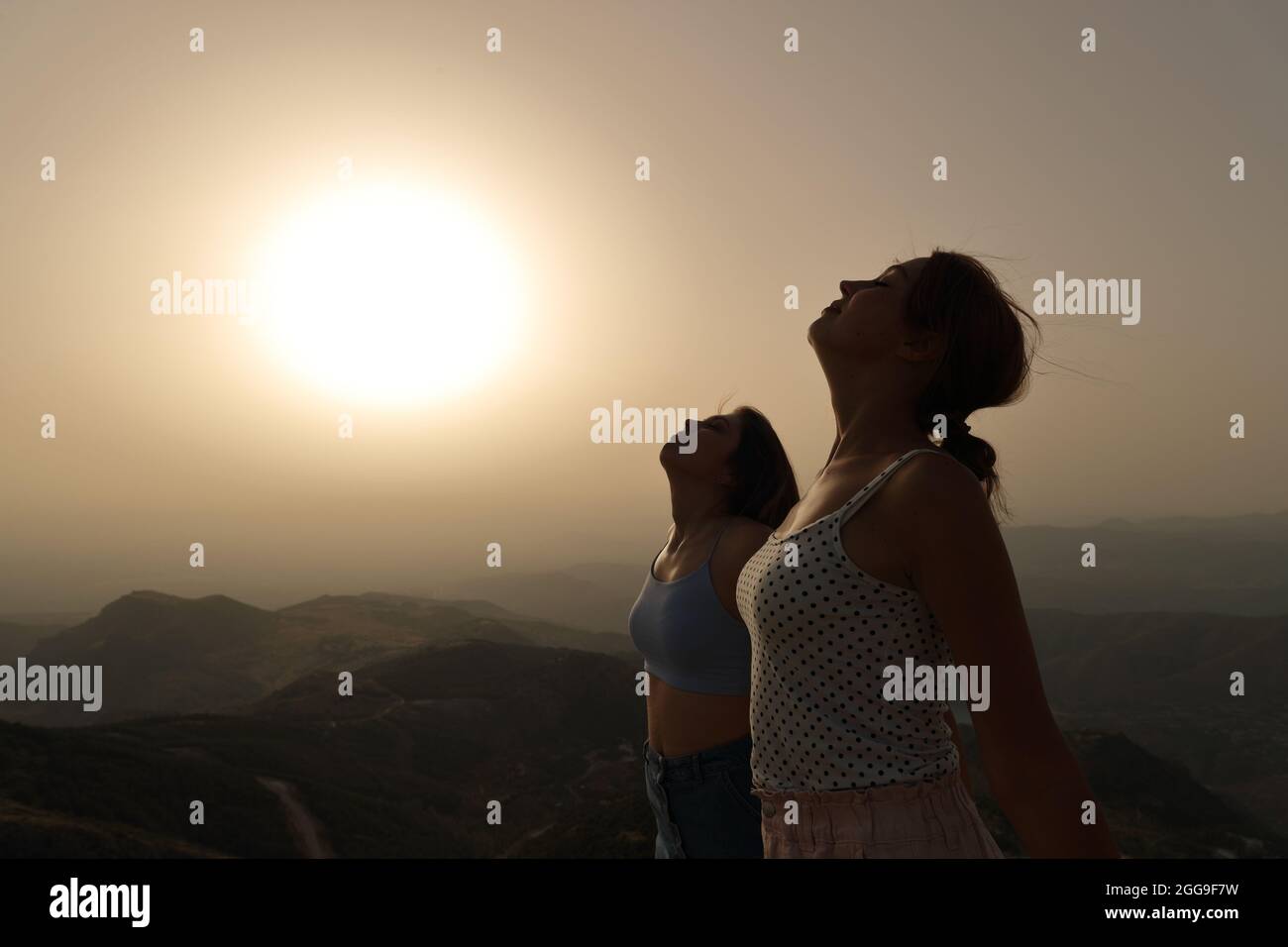 Vista laterale ritratto di due donne silhouette respirare aria fresca insieme al tramonto Foto Stock
