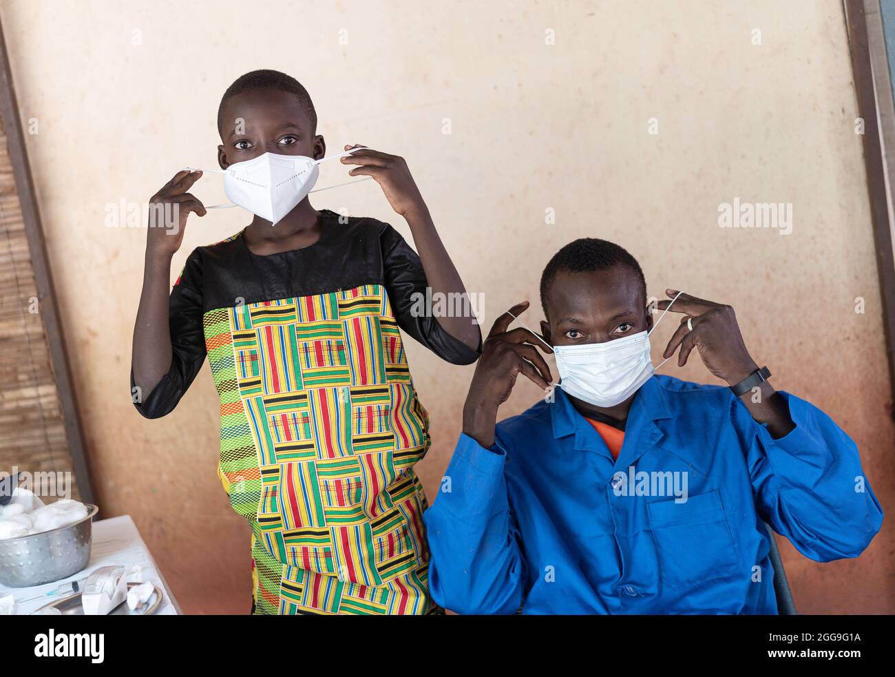Nero africano ragazzo e medico mostrando come indossare correttamente una maschera protettiva per prevenire l'infezione virale Foto Stock